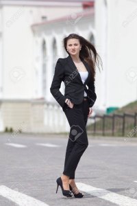 13301079-brunette-on-stiletto-heels-outdoors-young-woman-in-black-suit-walking-along-the-cross...jpg
